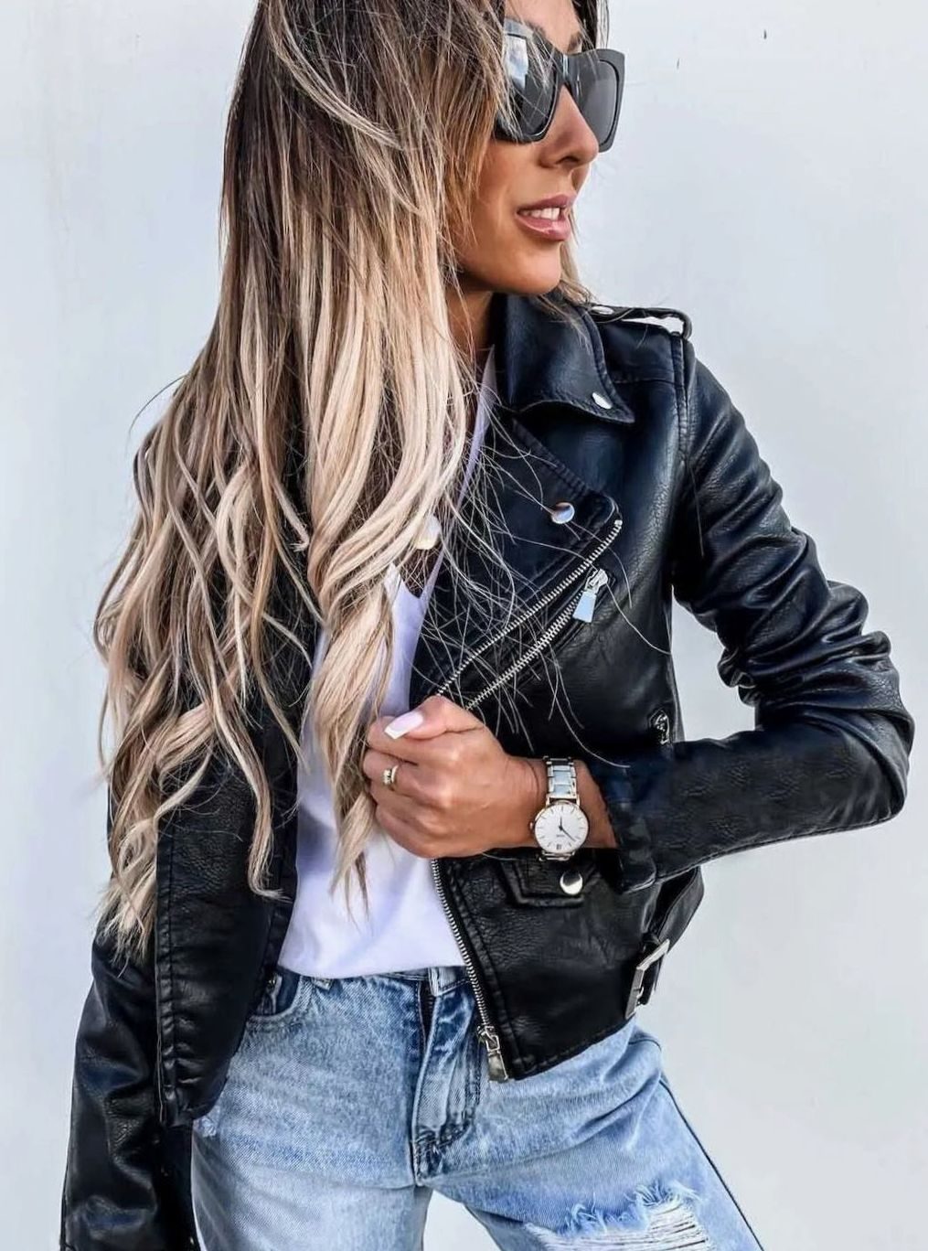 Mujer luciendo cazadora biker entallada combinada con vaqueros y camiseta blanca